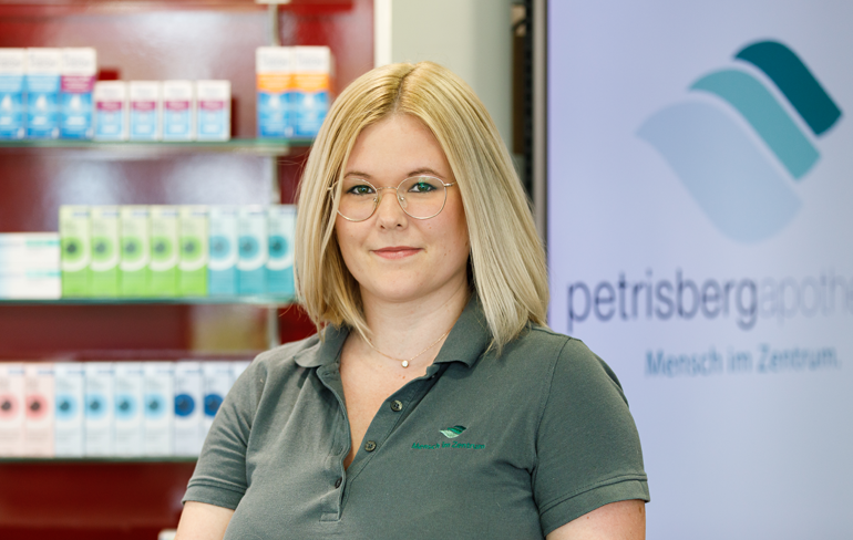 Eine Apothekerin der Petrisberg Apotheke steht vor einem Medikamentenregal.