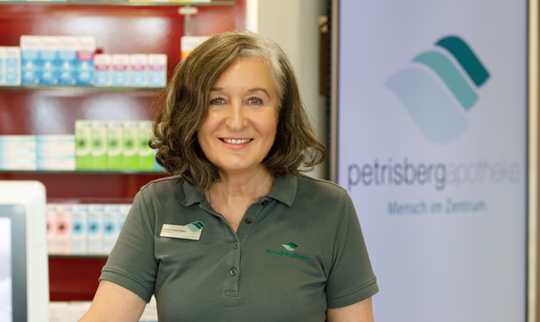 Eine Apothekerin der Petrisberg Apotheke steht am Tresen und schaut in die Kamera.